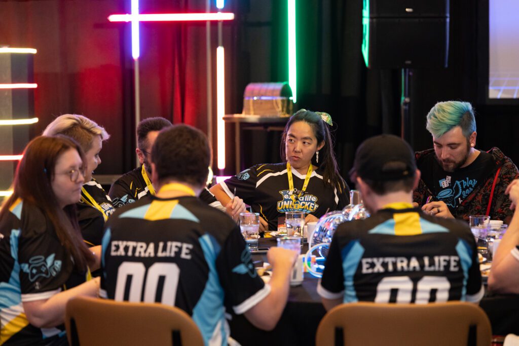 Group of Extra Life participants in their Extra Life jerseys sitting at a table.